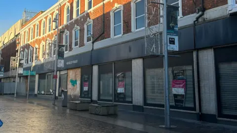 North East Lincolnshire Council A street view of the former House of Fraser store. The windows have shutters down inside the shop and there are closing down posters in the windows.