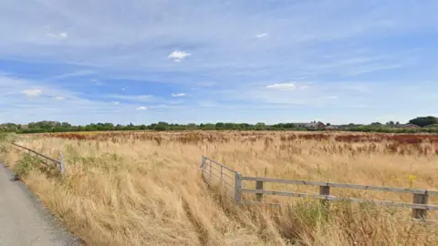 Google Grass fields and fences pictured against a background of a blue sky and clouds.