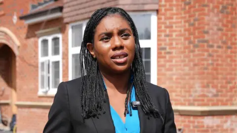 PA Media Conservative Party Leader Kemi Badenoch, wearing a blue shirt and black jacket, speaks at a London housing project. 