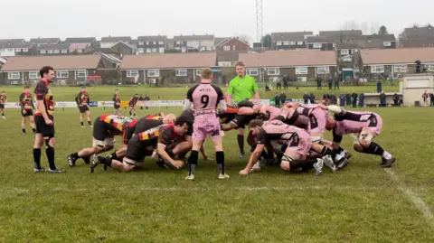 Clifton RFC and Cinderford RFC teams locked in a scrum during a game