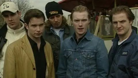 Five handsome chaps stood in front of the queues to a theme park ride