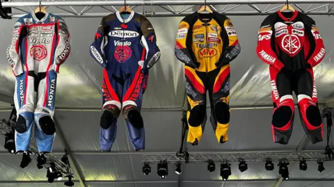 Four sets of leathers hanging from the ceiling in the display.