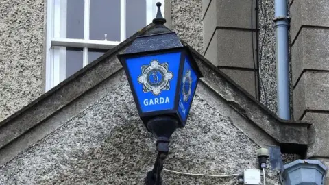 A blue and black Garda light sits on a grey stone wall