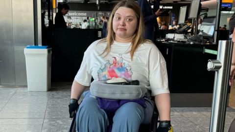 Amy in her wheelchair at Heathrow Airport looking visibly frustrated