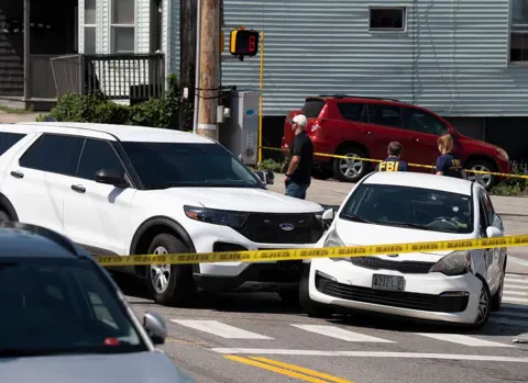 Two white cars that collided are behind yellow tape
