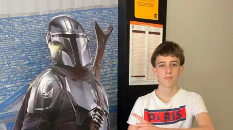 A boy posing with a cutout of a Star Wars character
