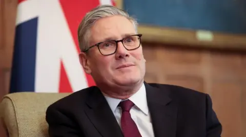 Sir Keir Starmer wearing a suit in front of a union flag. He is looking into the distance