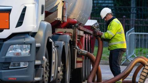 A HGV driver makes a fuel delivery at a petrol station 