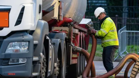 Dominic Lipinski/PA A HGV driver makes a fuel delivery at a petrol station 