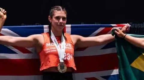 @inov8 A girl standing on a podium with medals around her neck, is holding a large union jack flag.