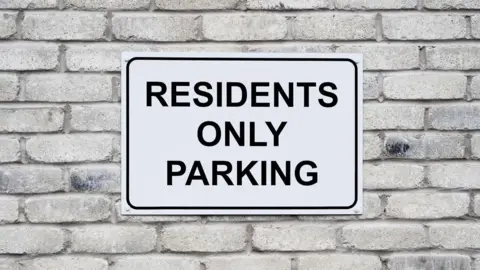A white sign which says residents only parking
