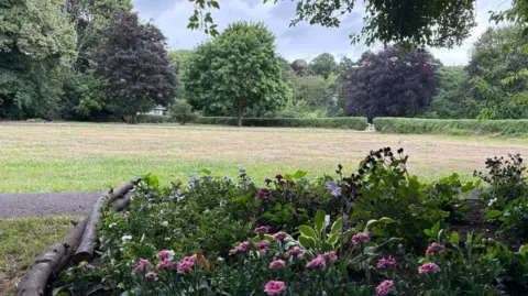 Steve Lindsay A bed of pink flowers with a path and Elvet Bowling Green's neatly-cut grassland behind.