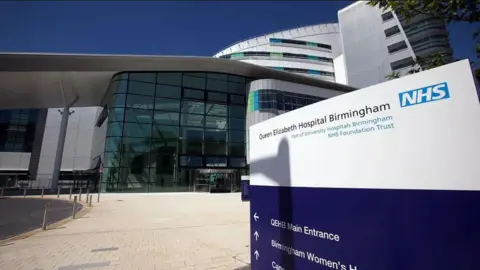 Getty Images Queen Elizabeth Hospital Birmingham, showing a blue and white sign on the concourse outside, with the main building behind 