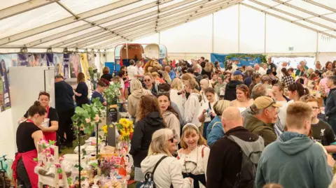 CJS PHOTOGRAPHY A marquee packed with people looking at local products.