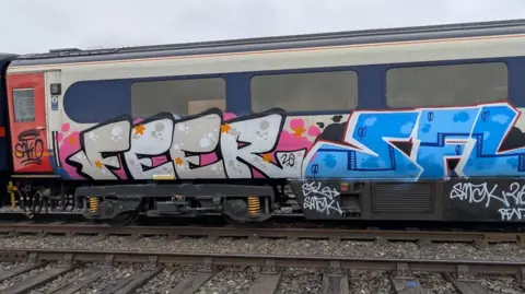 A rail coach covered in big, bold, multicoloured paint.