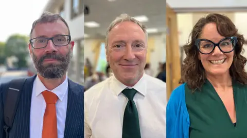 On the left, Deputy Aidan Matthews, a man with short brown hair a big bushy black and grey beard. He's wearing a blue pinstriped shirt, with a white shirt and an orange tie.
In the middle is Deputy Paul Montague, he's wearing a white shirt and a green tie.
On the right is Deputy Sarah Hansmann-Rouxel, she's got wavy brown hair, big blue glasses and a big toothy smile. She's wwearing a blue jumper over a green top.