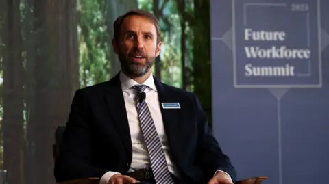 PA Media Sir Gareth Southgate wearing a suit and tie, sitting on a chair in front of a backdrop which reads "Future Workforce Summit"