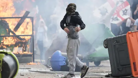 Getty Images A man in a riot in Rotherham, with fire in the background