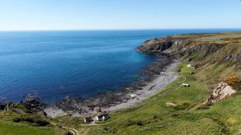 A view across a sweeping south of Scotland bay with cottages on the shore and the sea in front