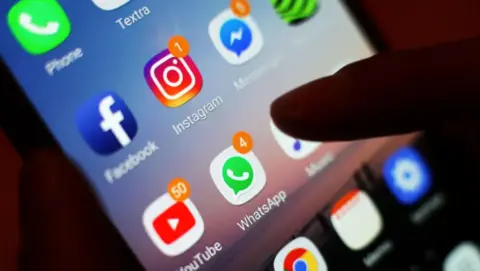 BBC An anonymous hand pressing the screen of a phone.