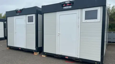 Two cuboid shaped units with a white door and a small window.