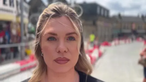 BBC/NATHAN TURVEY A picture of Emily Smallman, who has blonde shoulder length hair, standing in front of the roadworks.