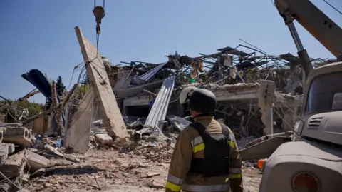 A Ukrainian emergency personnel works among the rubble of a destroyed hotel following a Russian strike in Kramatorsk