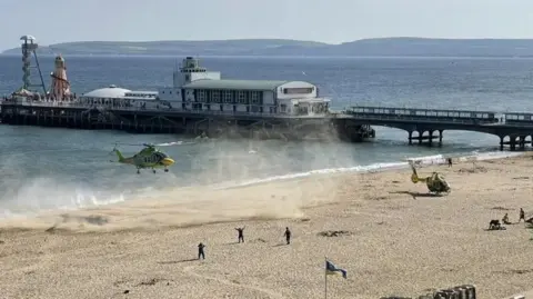 BUHALIS A helicopter landing on the beach near Bournemouth Pier