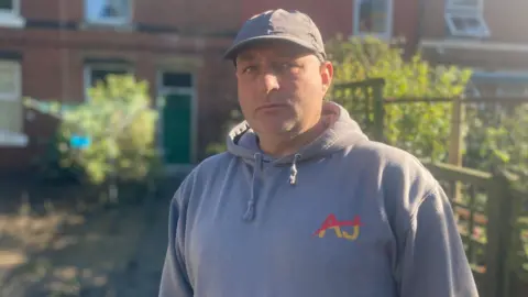 A man in a sports top stood in a garden