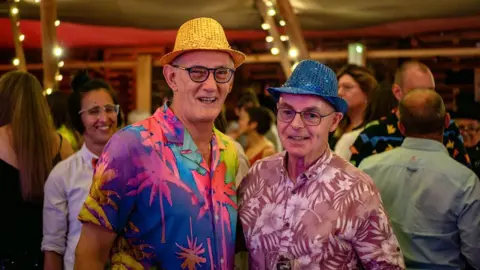 Sarah Hewitt Two older men in floral shirts and colourful hats