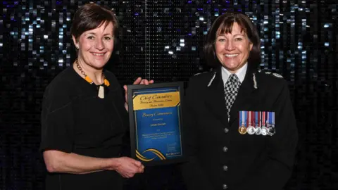 Police Scotland A woman holding a framed bravery certificate standing next to the female chief constable of Police Scotland