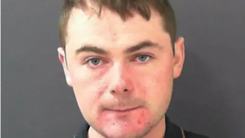 Police custody picture of a man with short dark hair.
