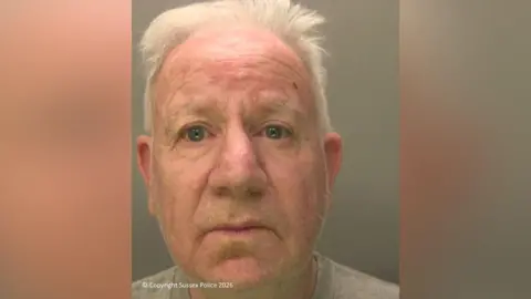 A man with grey hair, dark grey eyes and wearing a grey shirt.