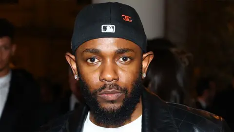 Getty Images Kendrick Lamar, a man at the Met Gala, wearing backwards hat, black leather jacket and white tshirt.