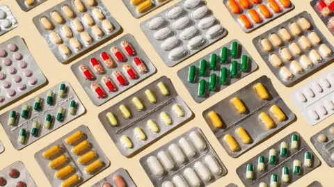 Pattern of blisters with colorful pills and capsules on beige background.