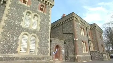 A grey brick building, with a blue sky in the background