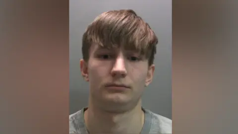 Cumbria Police A mugshot of Jack Crawley. He has short brown hair and is wearing a grey t-shirt.