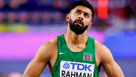 Imran Rahman A fit looking male  Asian athlete with a beard in a green vest