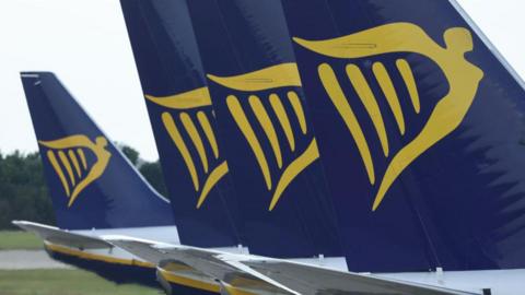 Tails of Ryanair planes with navy and gold branding featuring a logo combining images of an angel and a harp