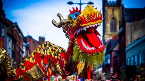 Culture Liverpool A large Chinese dragon costume, with Liverpool's bombed out church building in the background