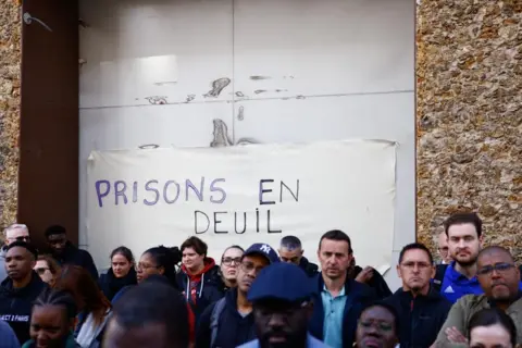 EPA A group of people standing outside La Santé prison with a sign that read 'prisons in mourning'