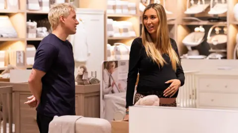 Hulu Jamie Laing and Sophie Habboo with her hand on her stomach in a baby cloth's shop