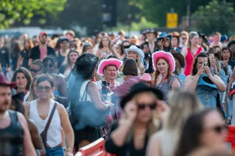 Getty Images A crowd of people, mostly female, two wearing pink cowboy hats.