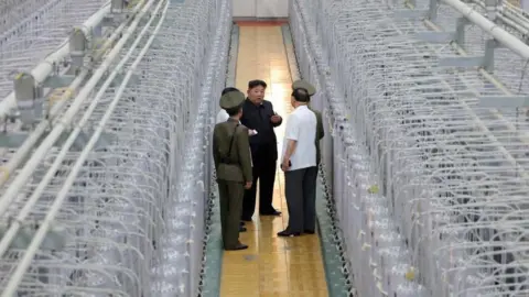 KCNA Kim walks past rows of centrifuges and talks to military officials at the Nuclear Weapons Institute