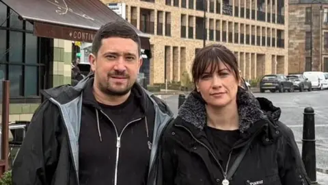 a couple in front of a restaurant by a road