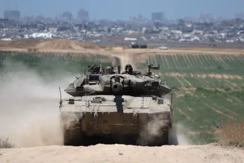 Tank patrols near Gaza with Jabalia in the background