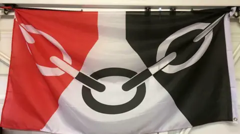 A red, white and black flag with an image of a chain running across it
