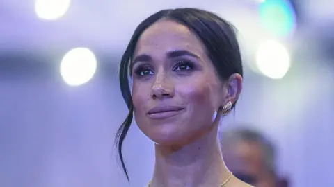 A close up of a woman with dark hair in an up-do and silver earrings
