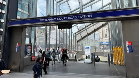 BBC/Harry Low People walk below a Tottenham Court Road station sign