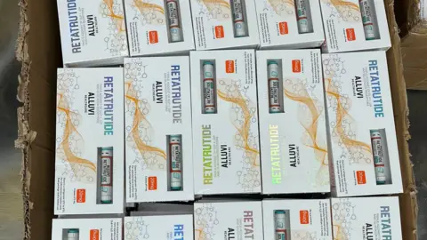 MHRA Boxes of fake weight loss medication, in boxes, with a weight loss pen in them. The boxes are white with writing on them. 